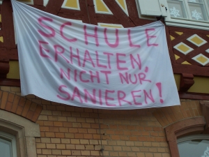 Schulgebäude mit Plakat